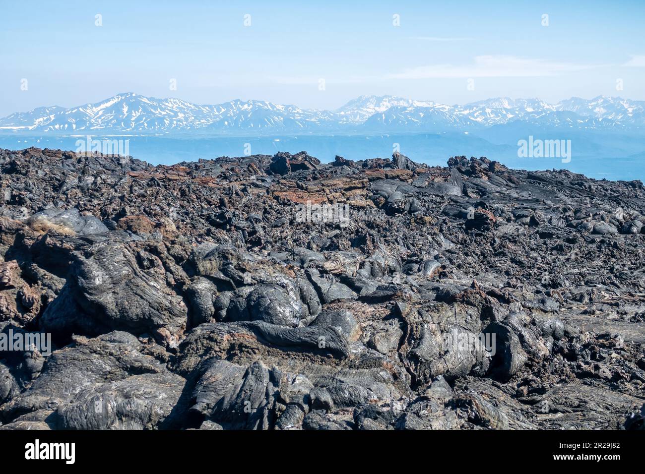 Extensive basalt fields (trappide) lava with fragmentary scoriae (trappide) against mountais. Spherulitic lava. Kamchatka, Russia Stock Photo