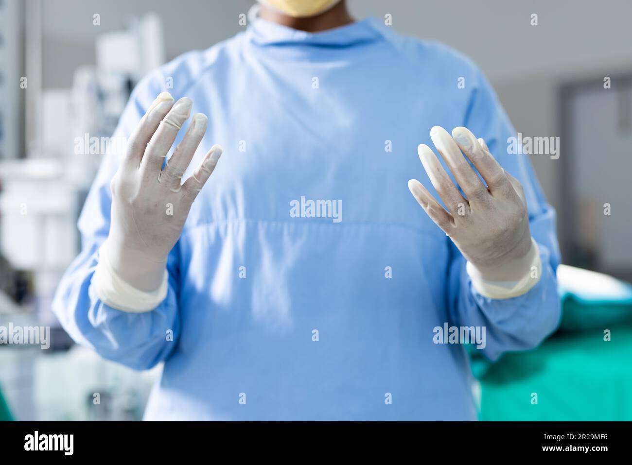 Midsection of surgeon wearing surgical gown and gloves in operating theatre Stock Photo