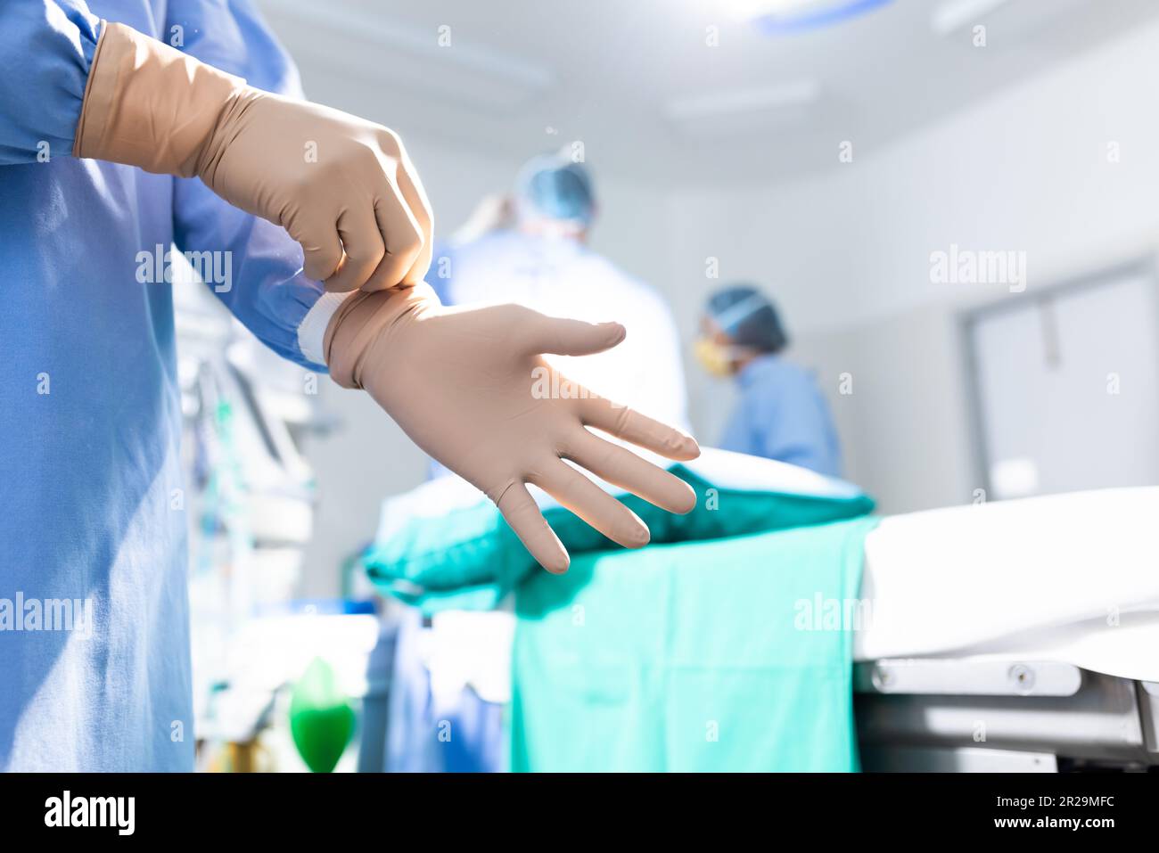 Midsection of surgeon putting on surgical gloves in operating theatre