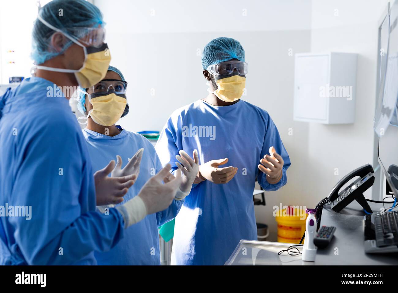 Diverse group of surgeons discussing x rays on screen in operating theatre Stock Photo