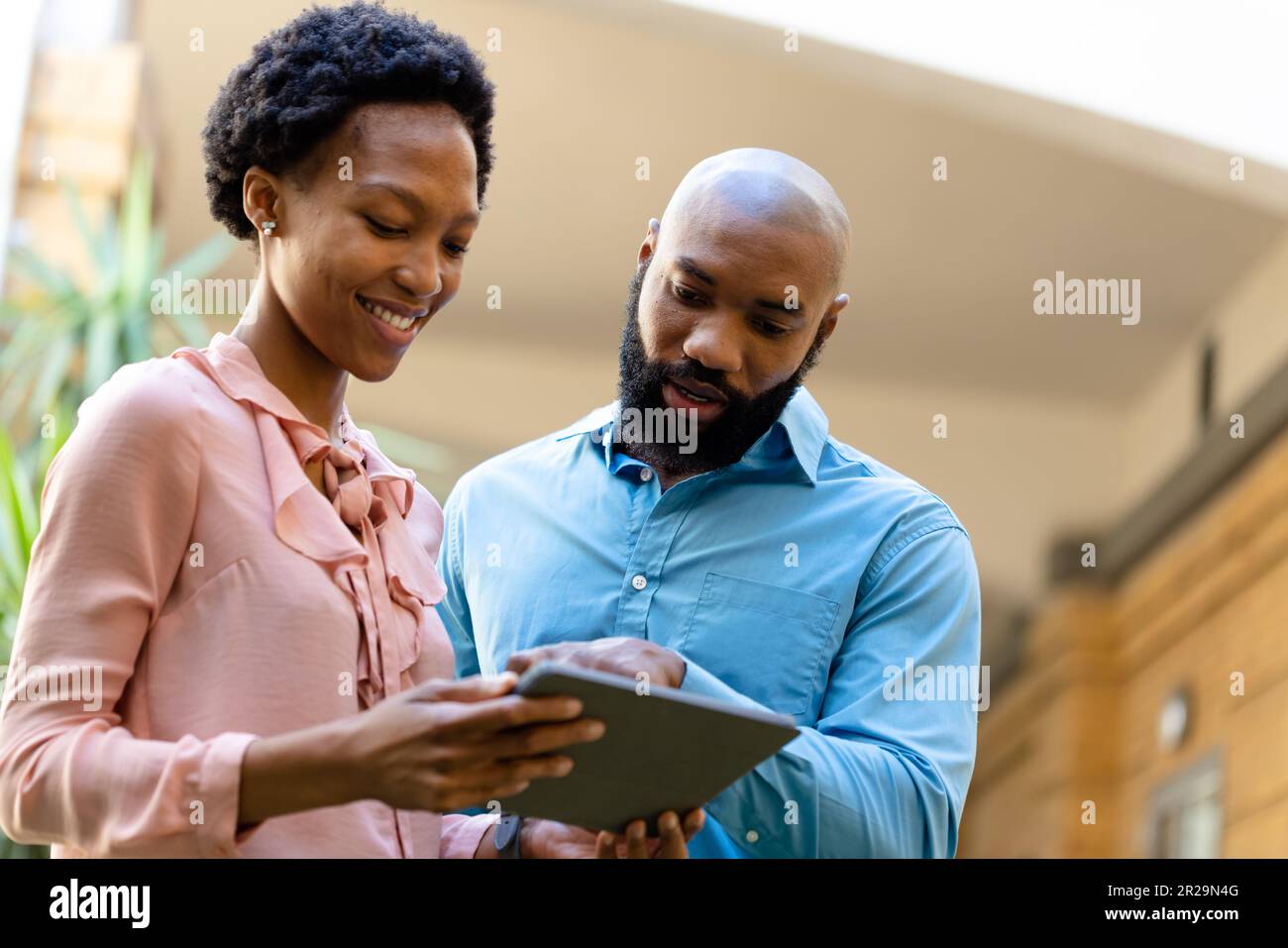 Low angle view of african american colleagues discussing over digital tablet outside office Stock Photo