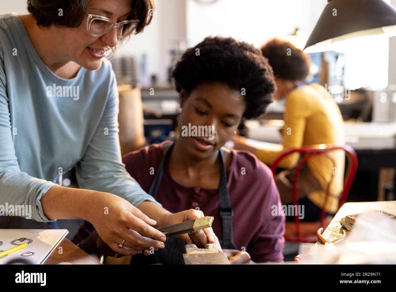 Happy diverse workers making jewellery using tools and talking at 