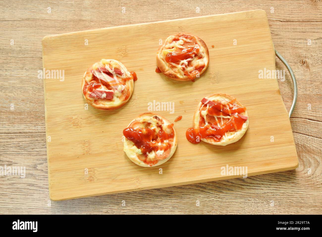 mini homemade pizza topping sausage and cheese on chopping block Stock Photo
