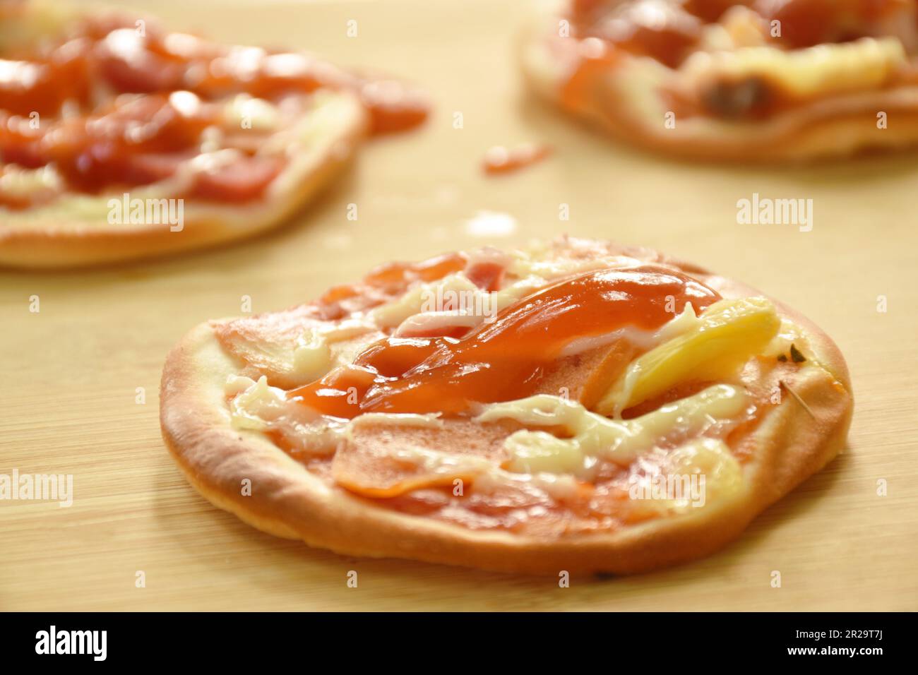 mini homemade pizza topping sausage and cheese on chopping block Stock Photo