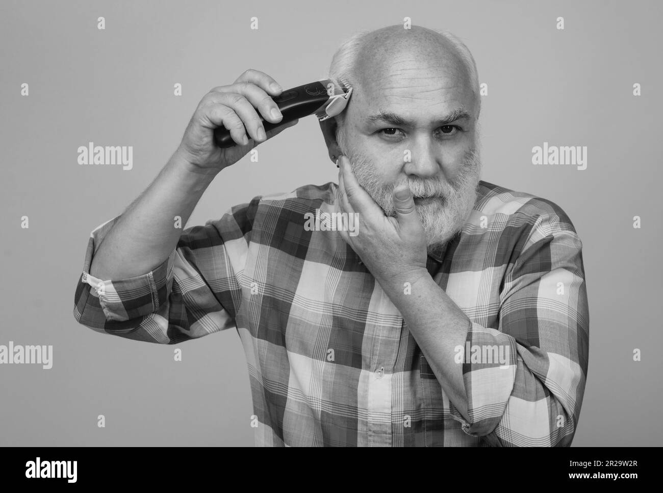 Portrait of senior man being trimmed with professional electric clipper