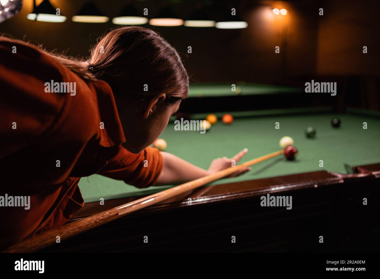 Female ball play snooker billiard player with cue aiming at the table ...
