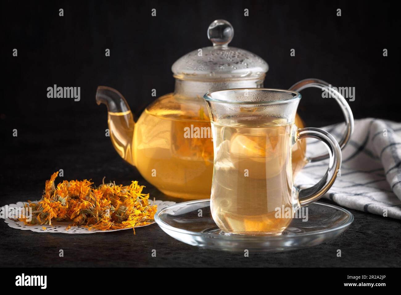 A teapot and a cup with healing tea. Dried marigold flowers. Stock Photo