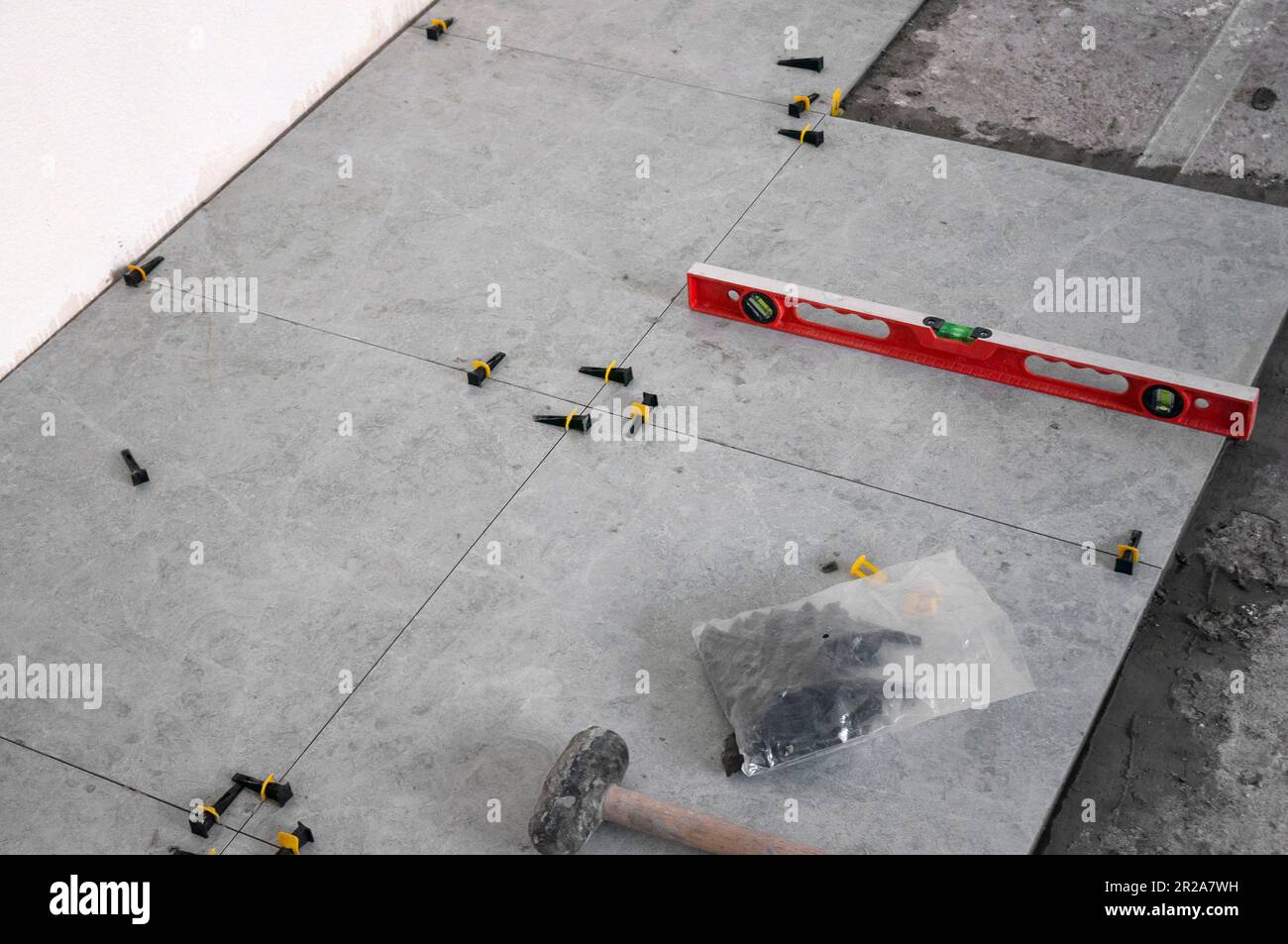 The process of laying tiles on the floor using tools and fixtures. Gray