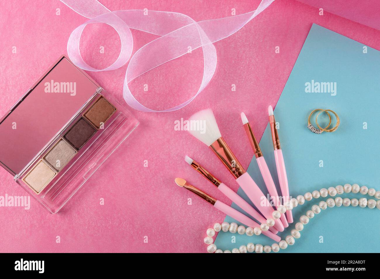 Beautiful still life of cosmetics, accessories and jewelry lying on a pink background. Stock Photo