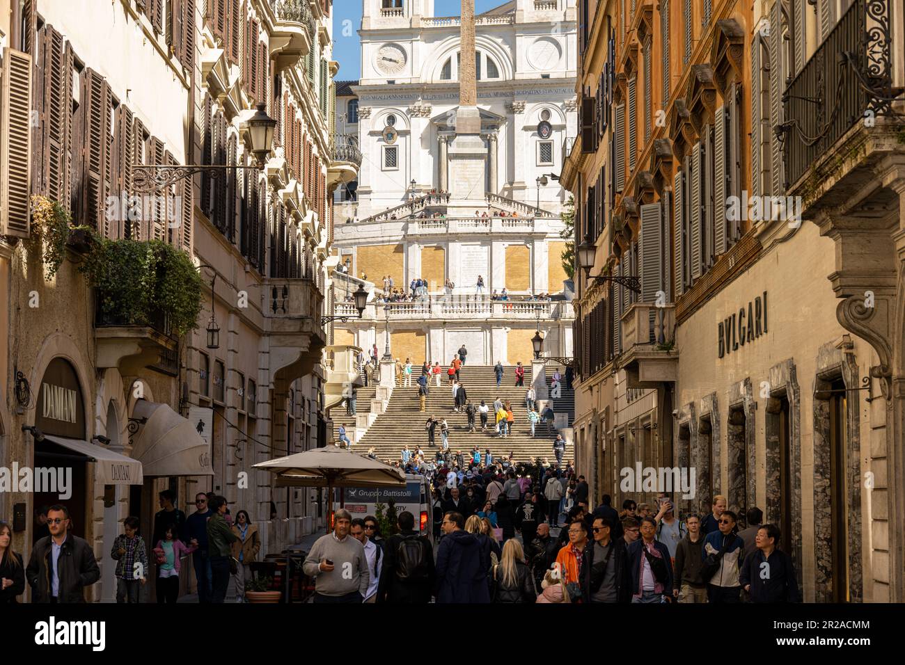 Rom, Italien, März 2023 Blick über die Via Condotti mit den exklusiven Geschäften im Schatten und die Spanische Treppe im Hintergrund im Sonnenlicht. Stock Photo