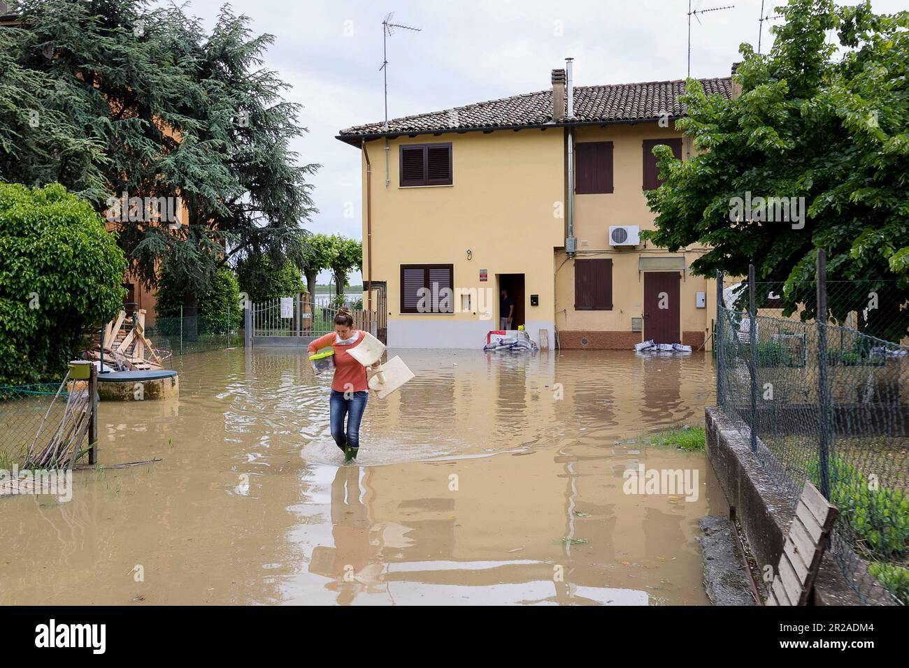 A woman carries her belongings in a flooded area near Bologna, Italy