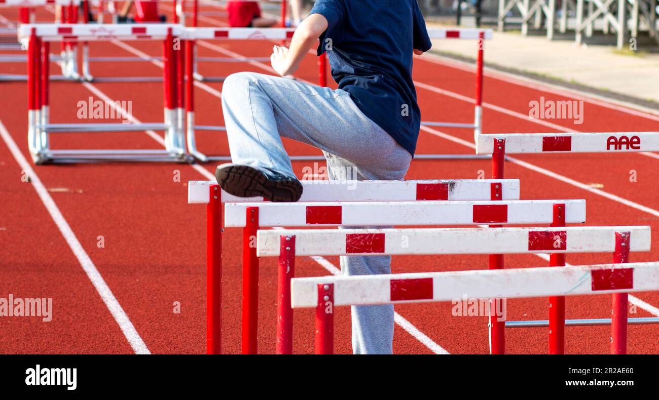 Rear view of one high school girl performing hurdle drills warming up