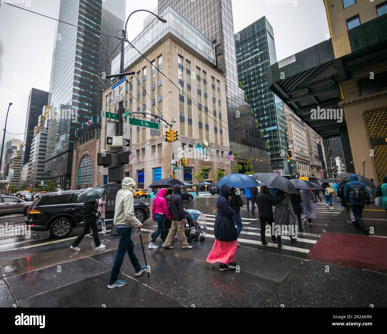 Tourists on Fifth Avenue in New York with their umbrellas across from Tiffany & Co.’s newly reopened store on Sunday, April 30, 2023. Weather from the Southeastern US and the Mississippi Valley has arrived in New York guaranteeing a sggy Sunday. (© Richard B. Levine) Stock Photo