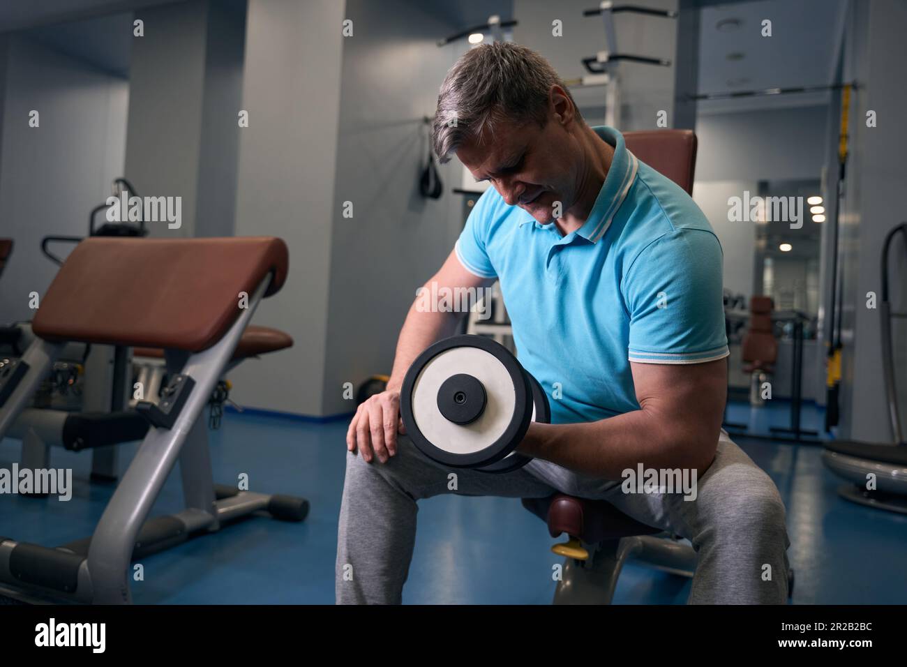 Serious concentrated bodybuilder doing strength training at gym Stock Photo