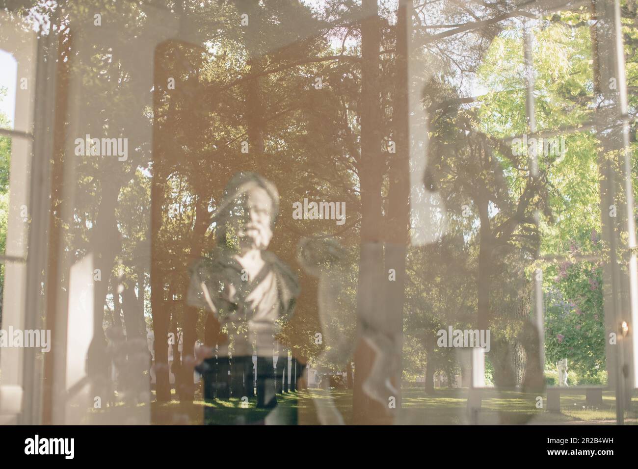 Statue behind the window of glass with reflection of beautiful garden ...