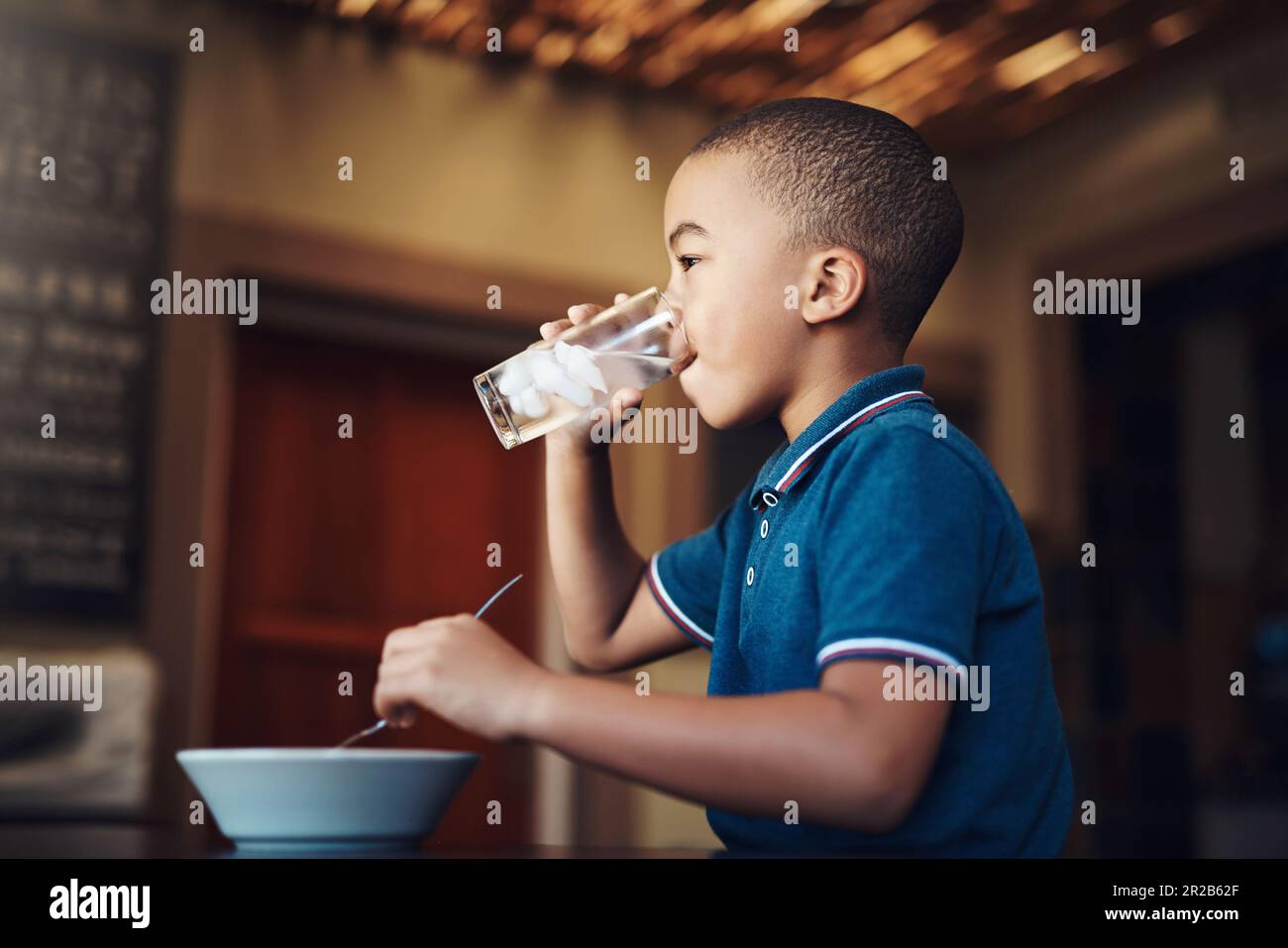 Water aids digestion. a young boy drinking water with his food at home