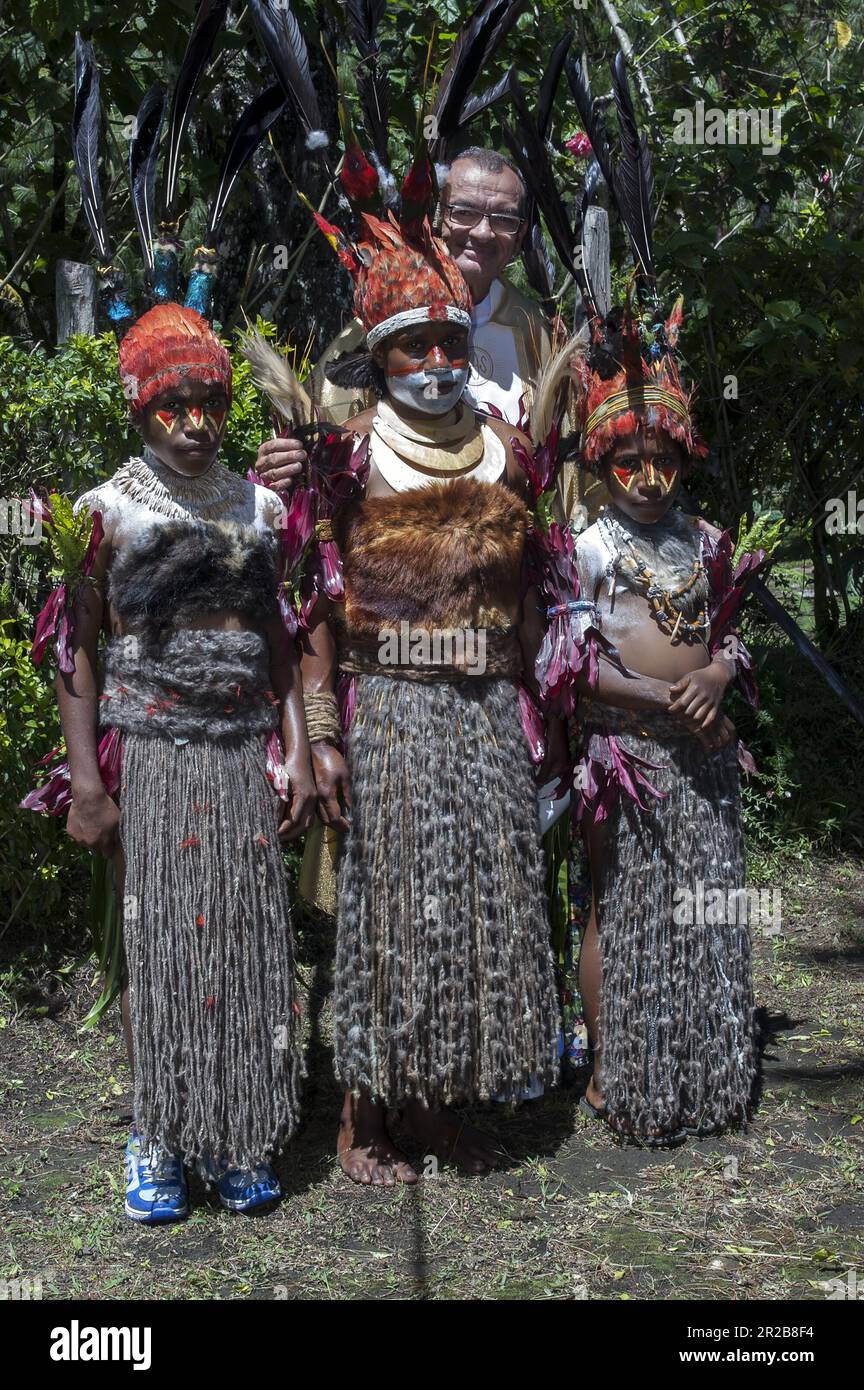 Papua New Guinea; Eastern Highlands; Goroka; three Papuan girls in traditional clothes with a white missionary 禮儀禮服的巴布亞女孩  儀式用の衣装を着たパプアの女の子 Stock Photo