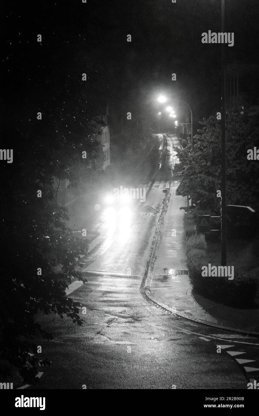 In the silent embrace of the night, a solitary car traverses the dimly
