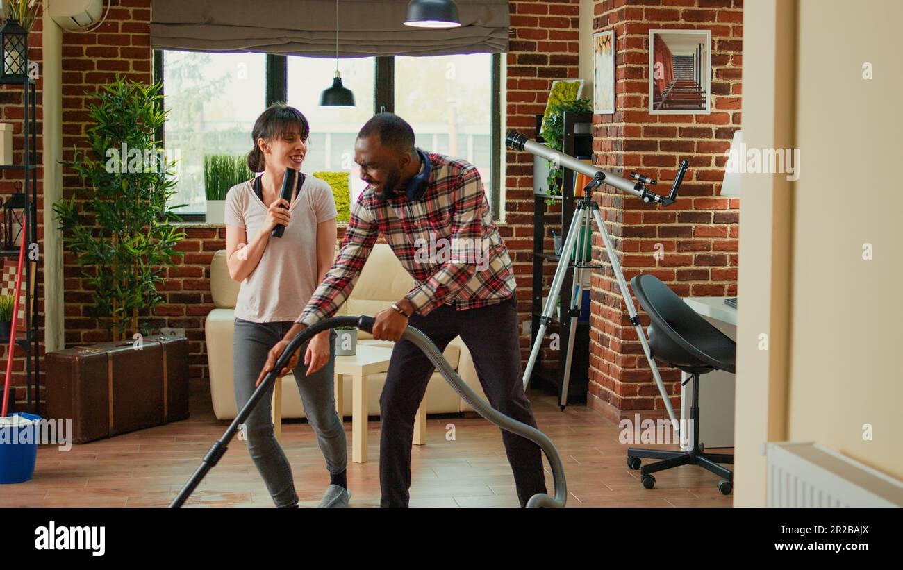Funny cheerful people singing song and cleaning living room floors