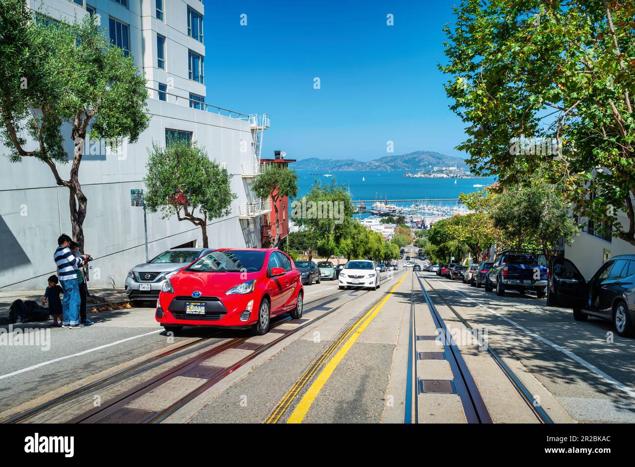 People take pictures at a steep street in downtown San Francisco