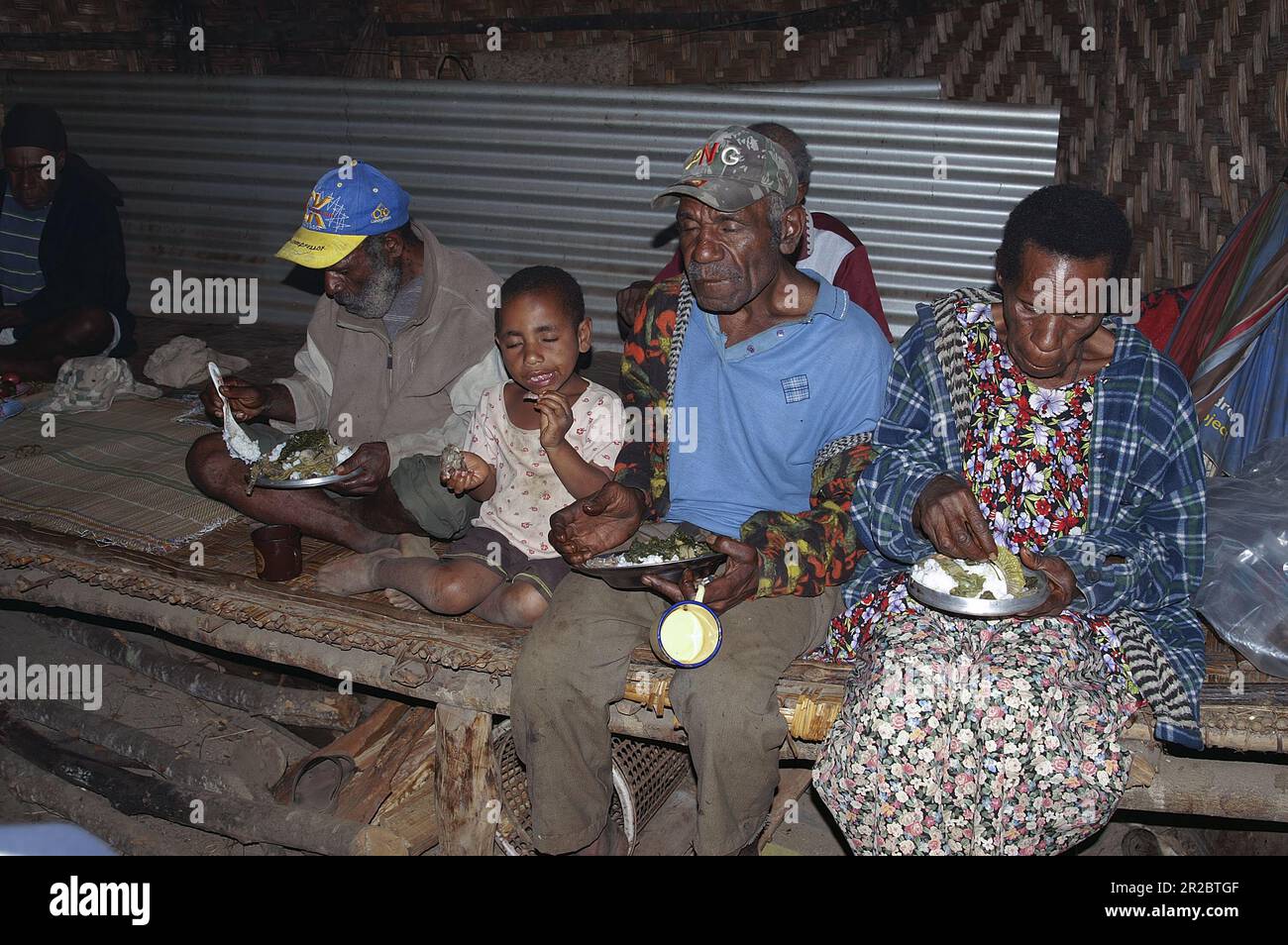 Papua New Guinea; Eastern Highlands; Goroka; The interior of a papuan hut - a family eats a meal; Innere Papua-Hütte – eine Familie isst eine Mahlzeit Stock Photo