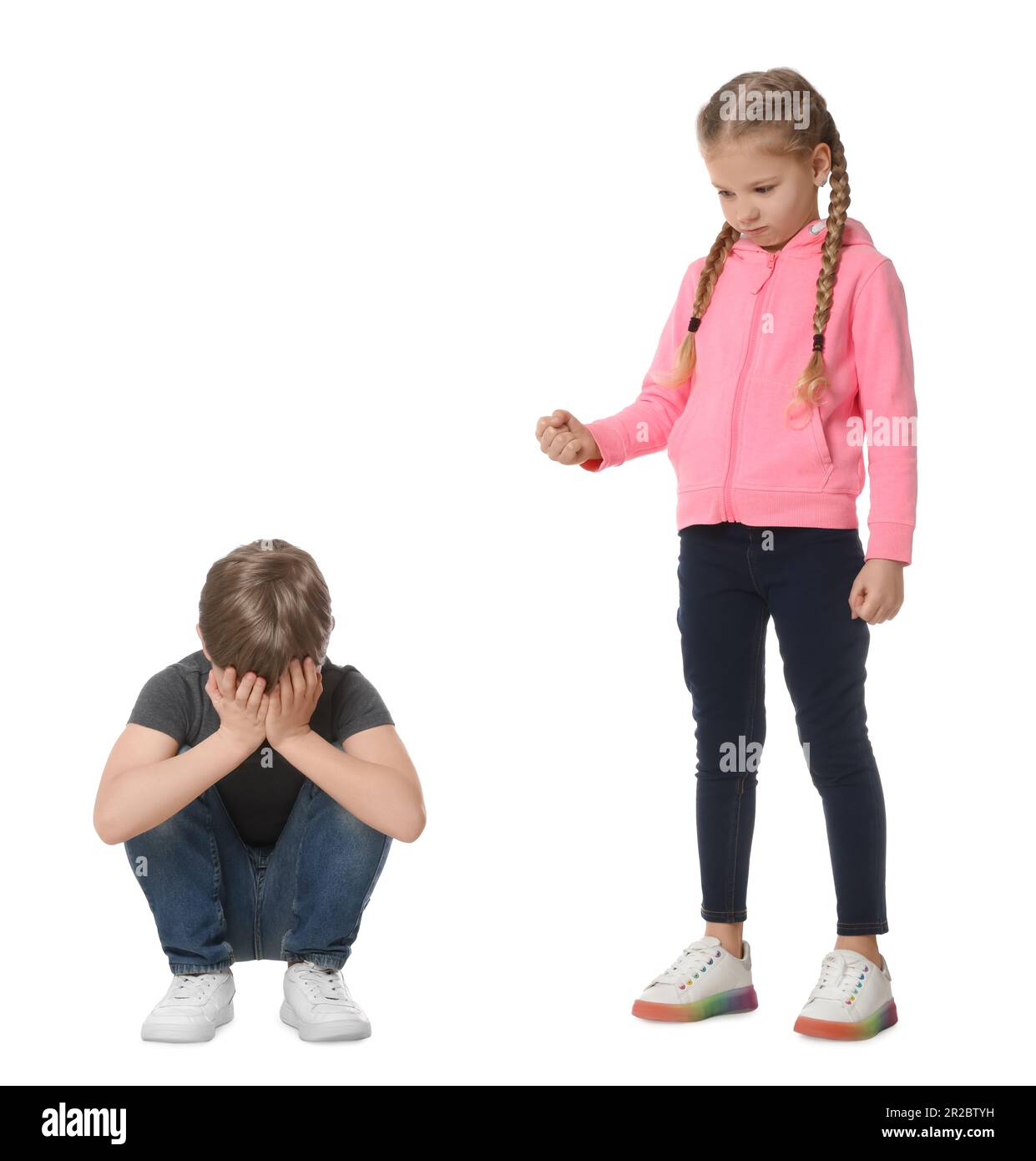 Girl with clenched fist looking at scared boy on white background. Children's bullying Stock Photo