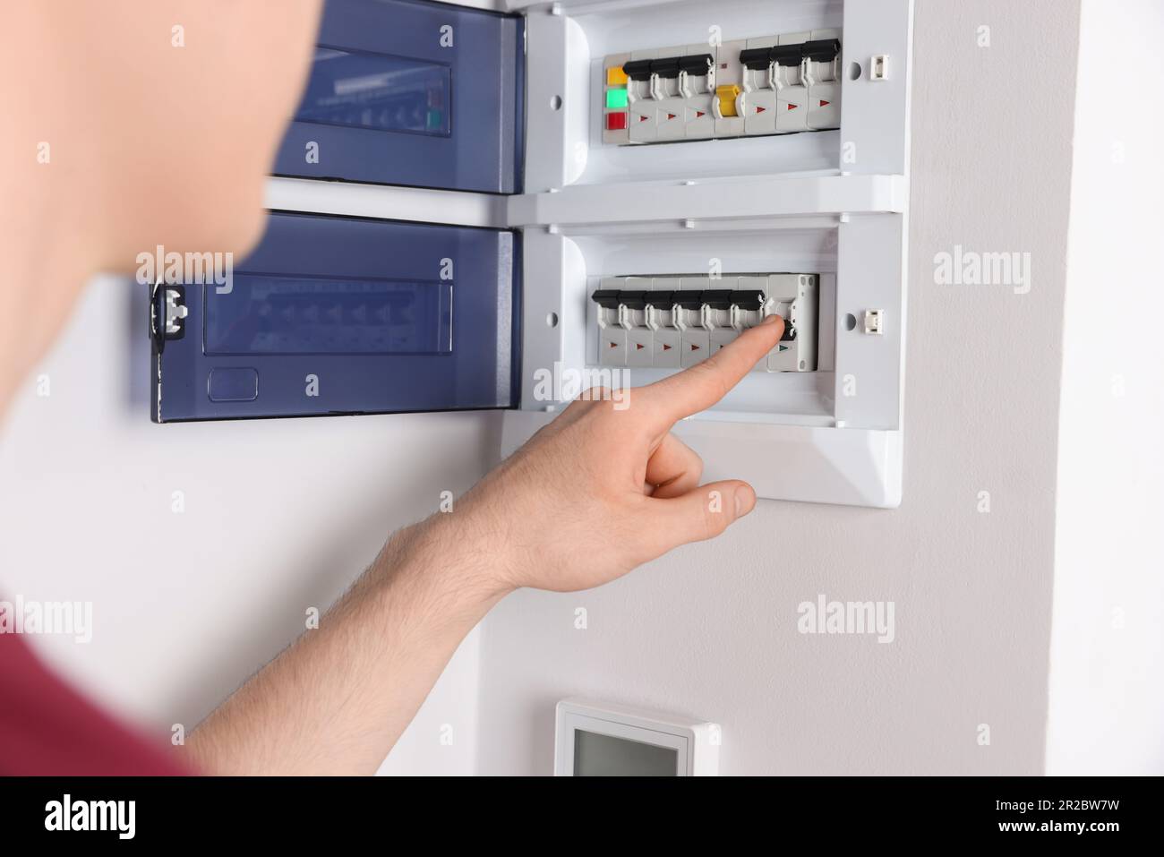 Handyman pressing switch on electrical panel board indoors, closeup
