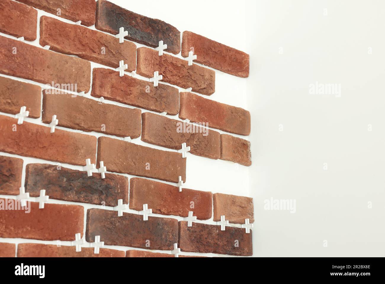 Decorative bricks with tile leveling system on white wall Stock Photo