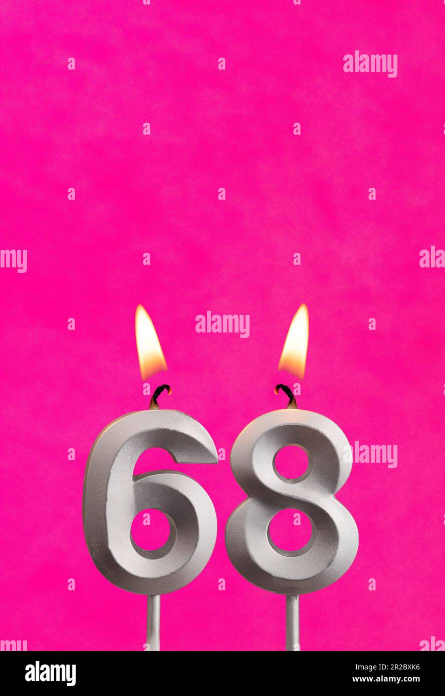 Candle 68 with flame - Silver anniversary candle on a fuchsia background Stock Photo