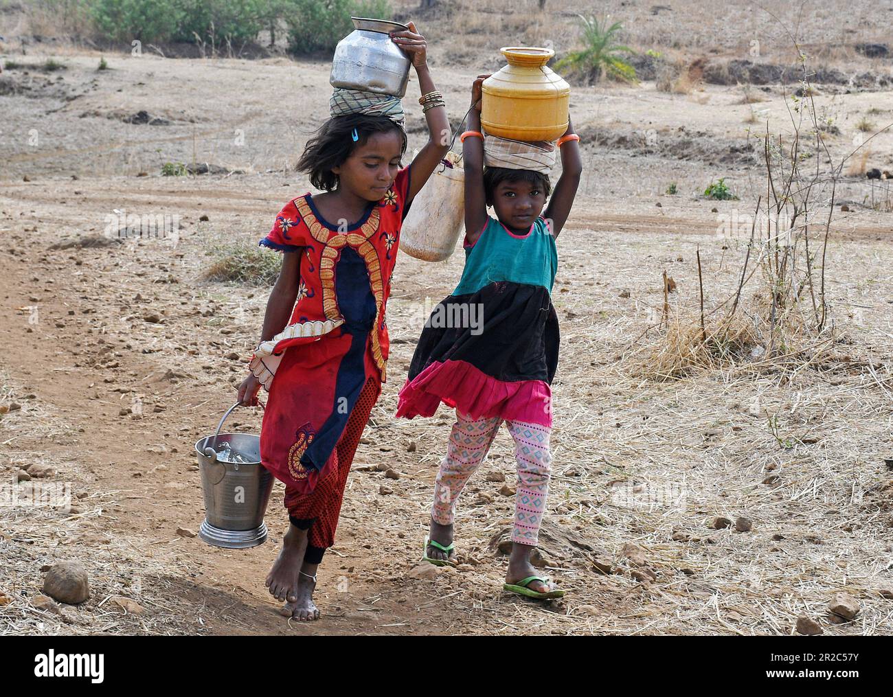 Mumbai, India. 16th May, 2023. Young girls carry pots of water after  filling it from the well on their head as they walk back home in Telamwadi  village near Vihigaon, Shahapur taluka