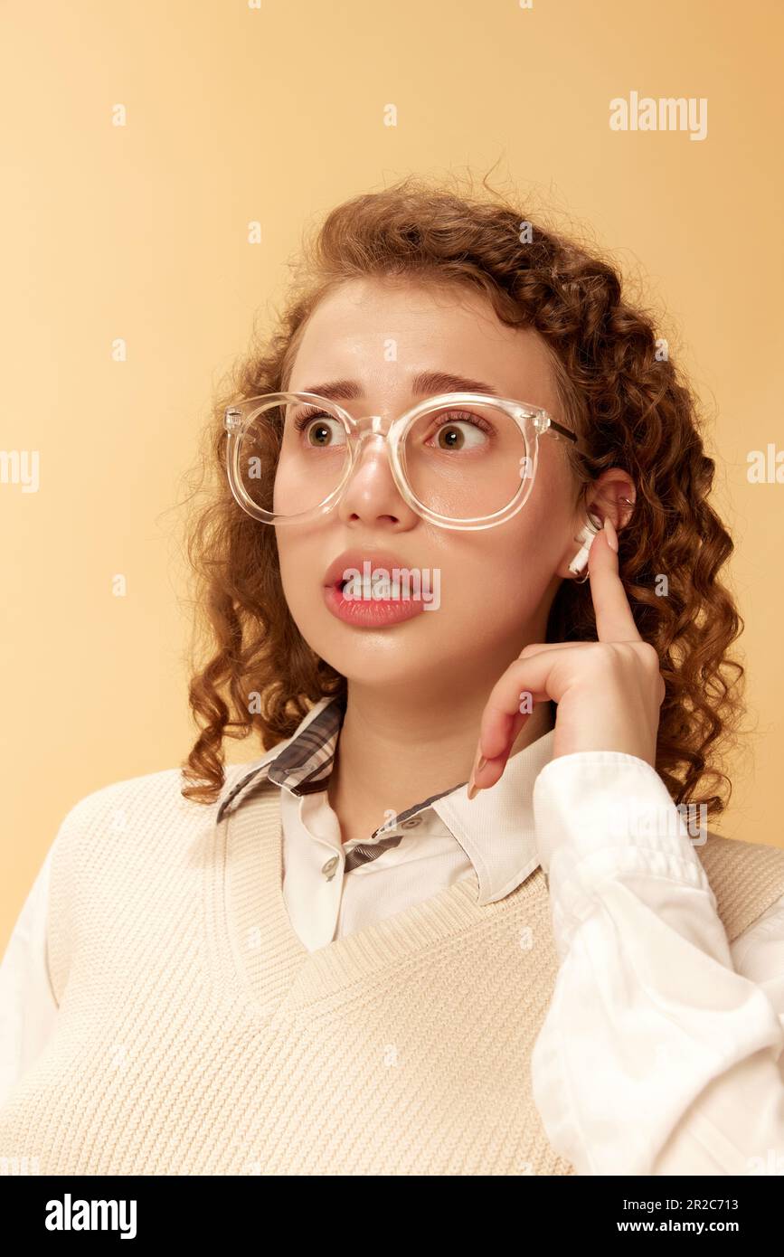 Portrait of young curly girl in white blouse and glasses, pressing on