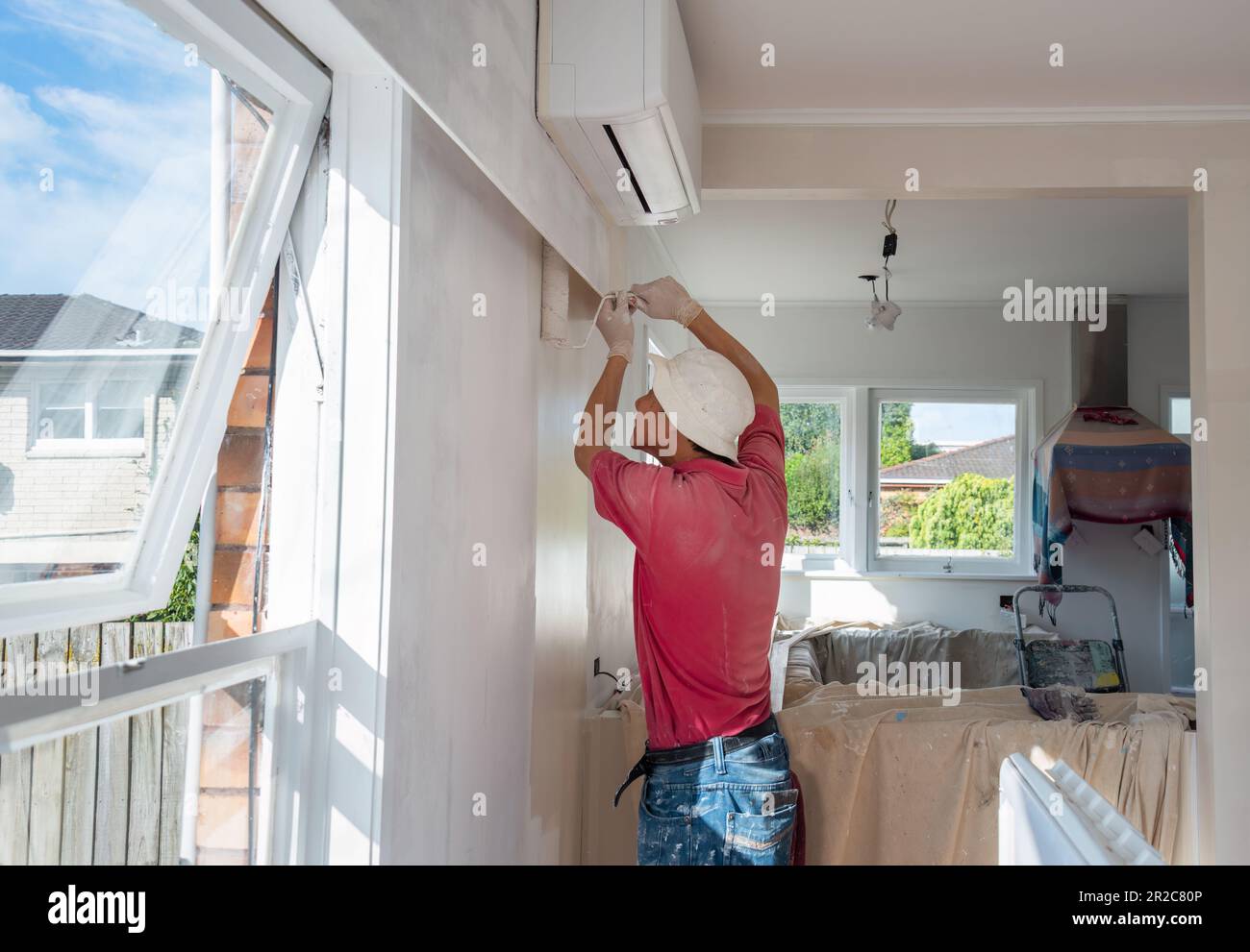 Man painting internal wall with a roller in a residential home. Home renovation project. Auckland. Stock Photo