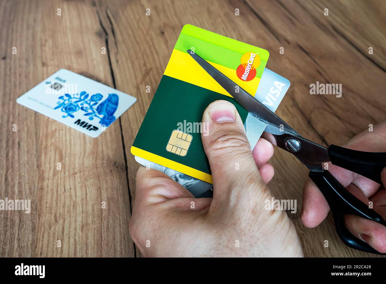 April 2, 2022. Barnaul. Russia: a man cuts bank credit cards of the type and mastercard with scissors. Destruction of plastic cards after the expirati Stock Photo