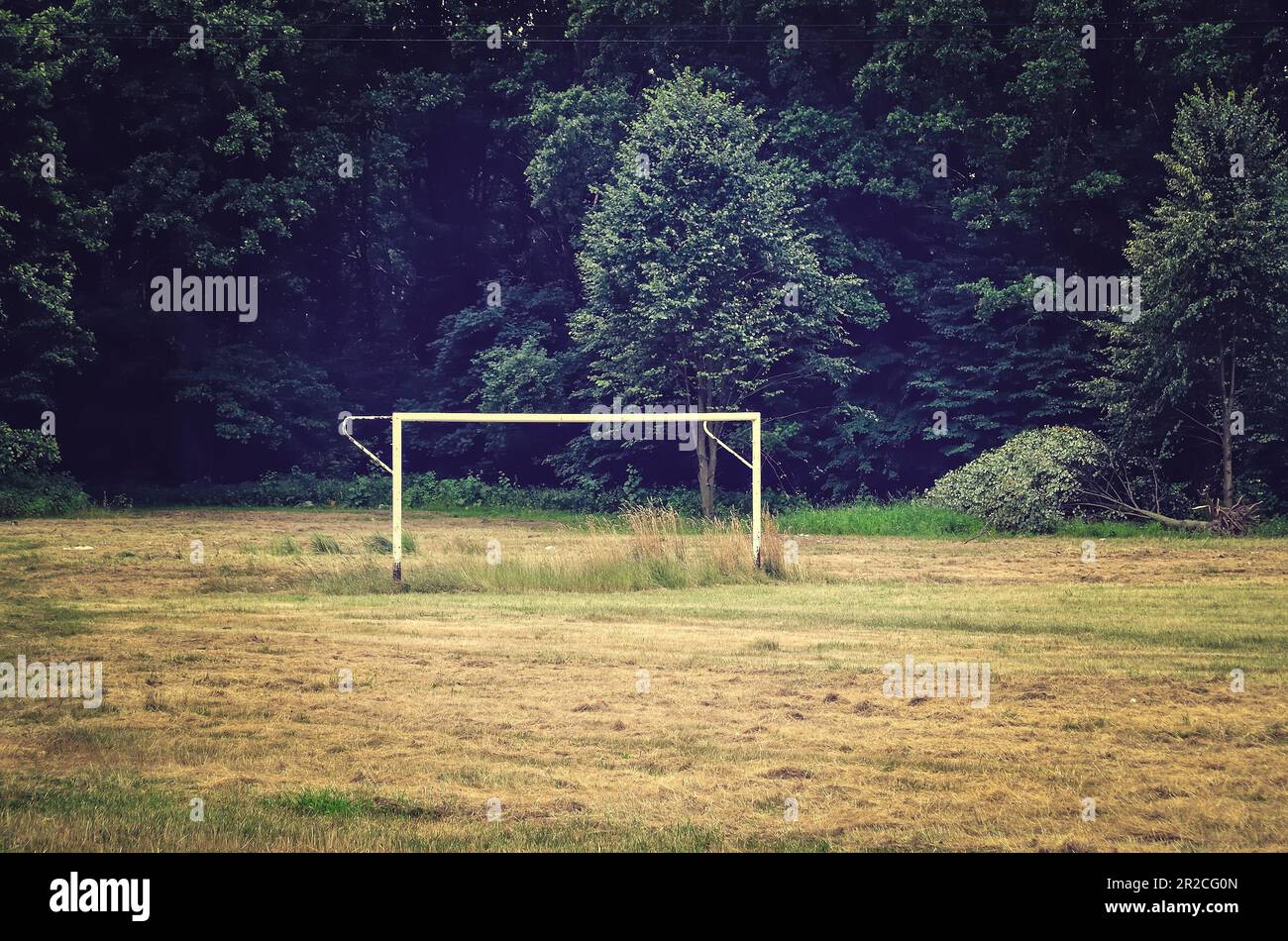 Football goal in an old-school setting. Soccer field and goal post on a meadow near to woods, soccer goal in a local residential area. Stock Photo