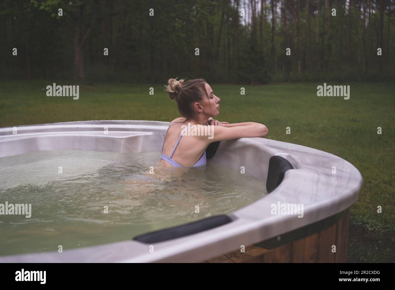 Young happy woman relaxing in hot tub. Enjoying welness SPA outside in the forests. Hot bath SPA. High quality photo Stock Photo