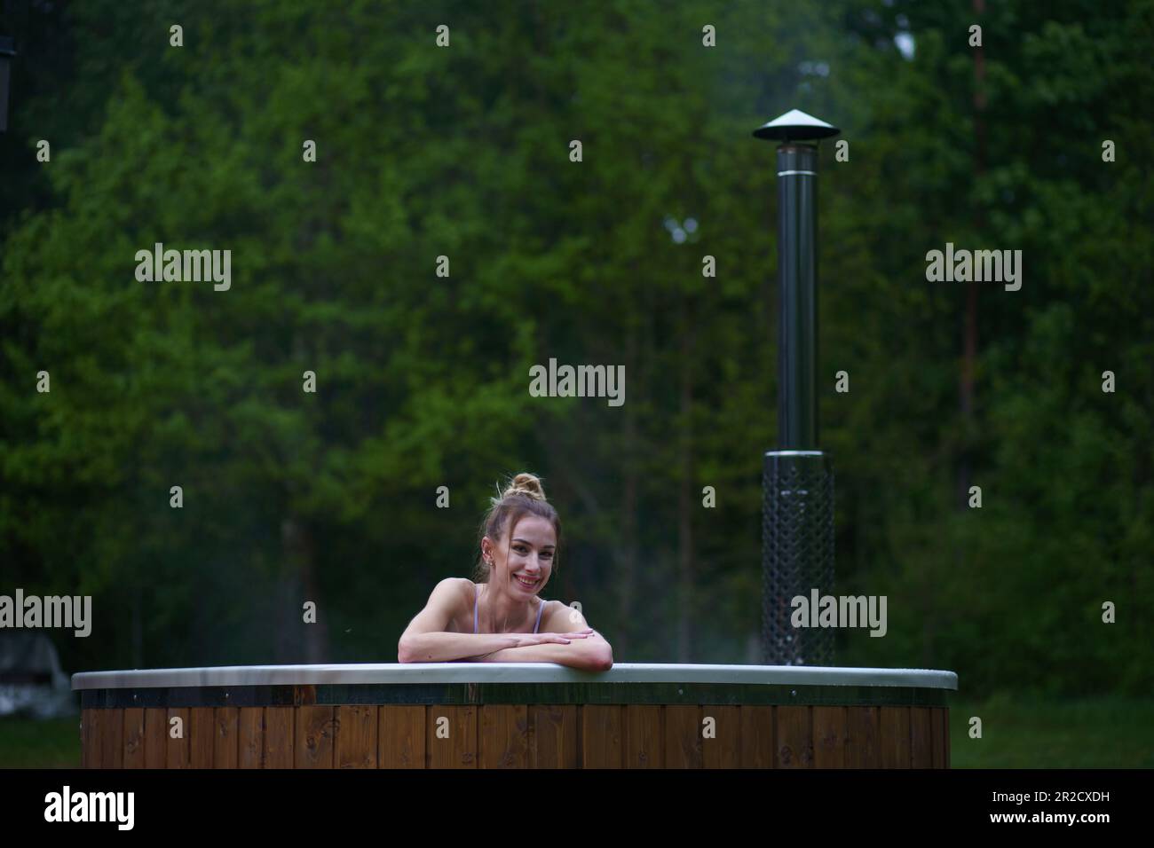 Young happy woman relaxing in hot tub. Enjoying welness SPA outside in the forests. Hot bath SPA. High quality photo Stock Photo