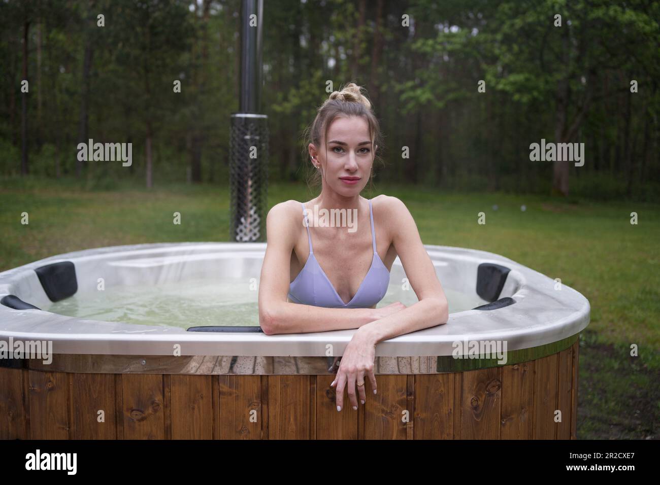 Young happy woman relaxing in hot tub. Enjoying welness SPA outside in the forests. Hot bath SPA Stock Photo