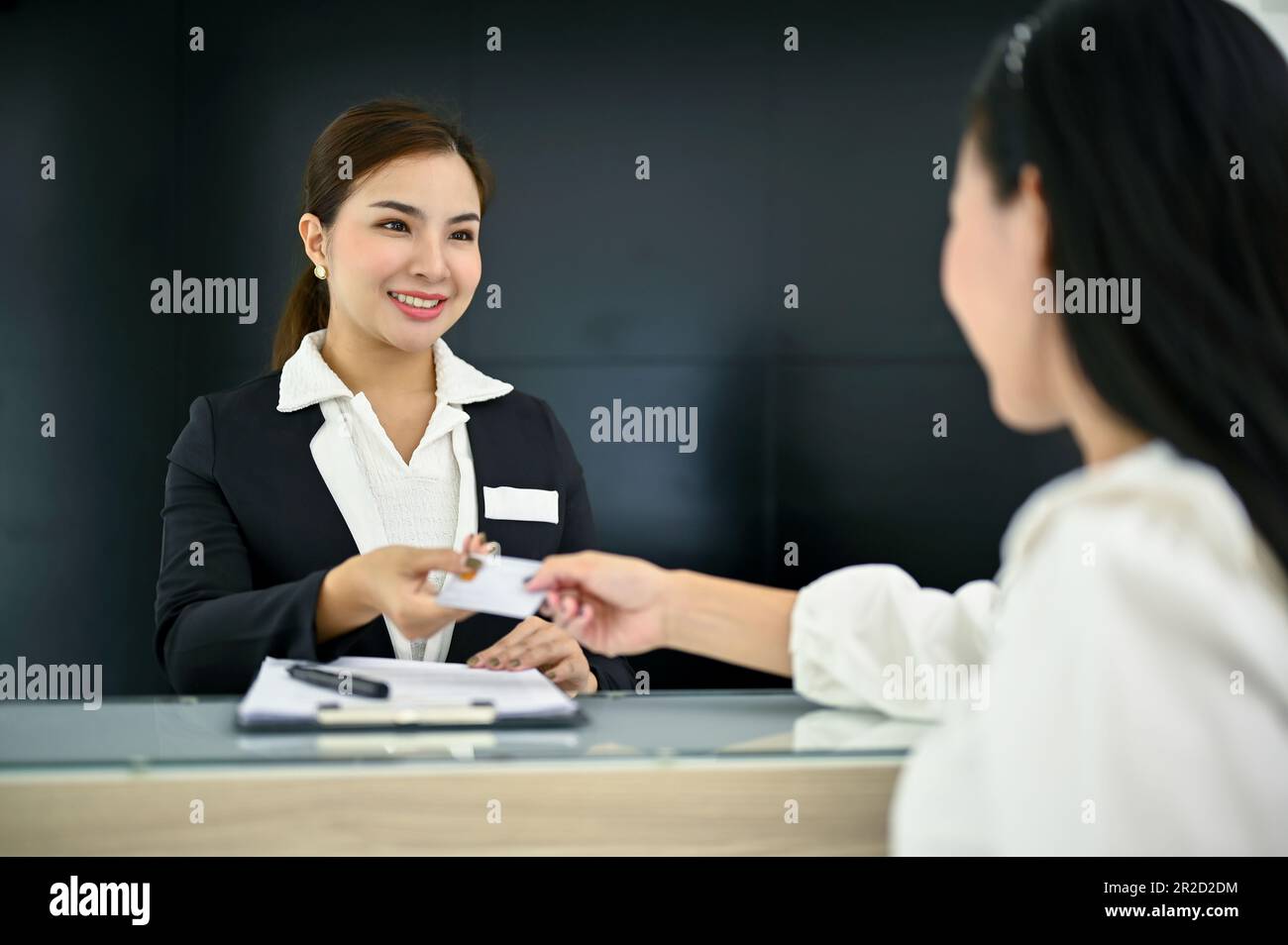 Friendly and beautiful millennial Asian female receptionist greeting
