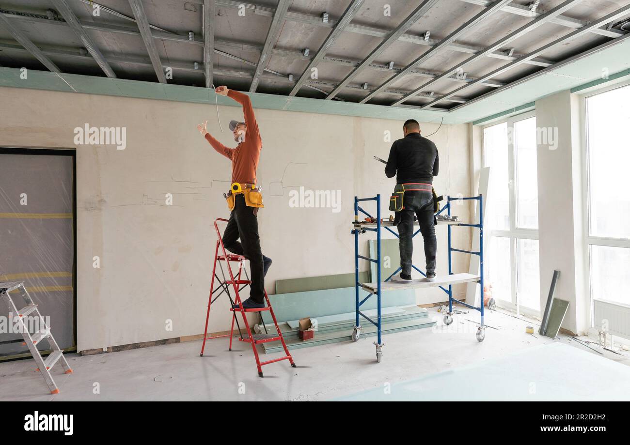 Builder fastens profile using cordless screwdriver Stock Photo