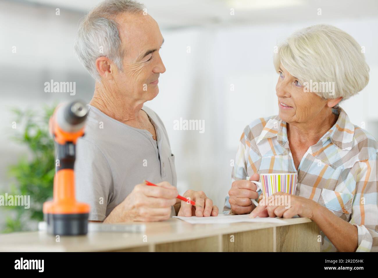 senior couple using electronic drill install cabinet Stock Photo