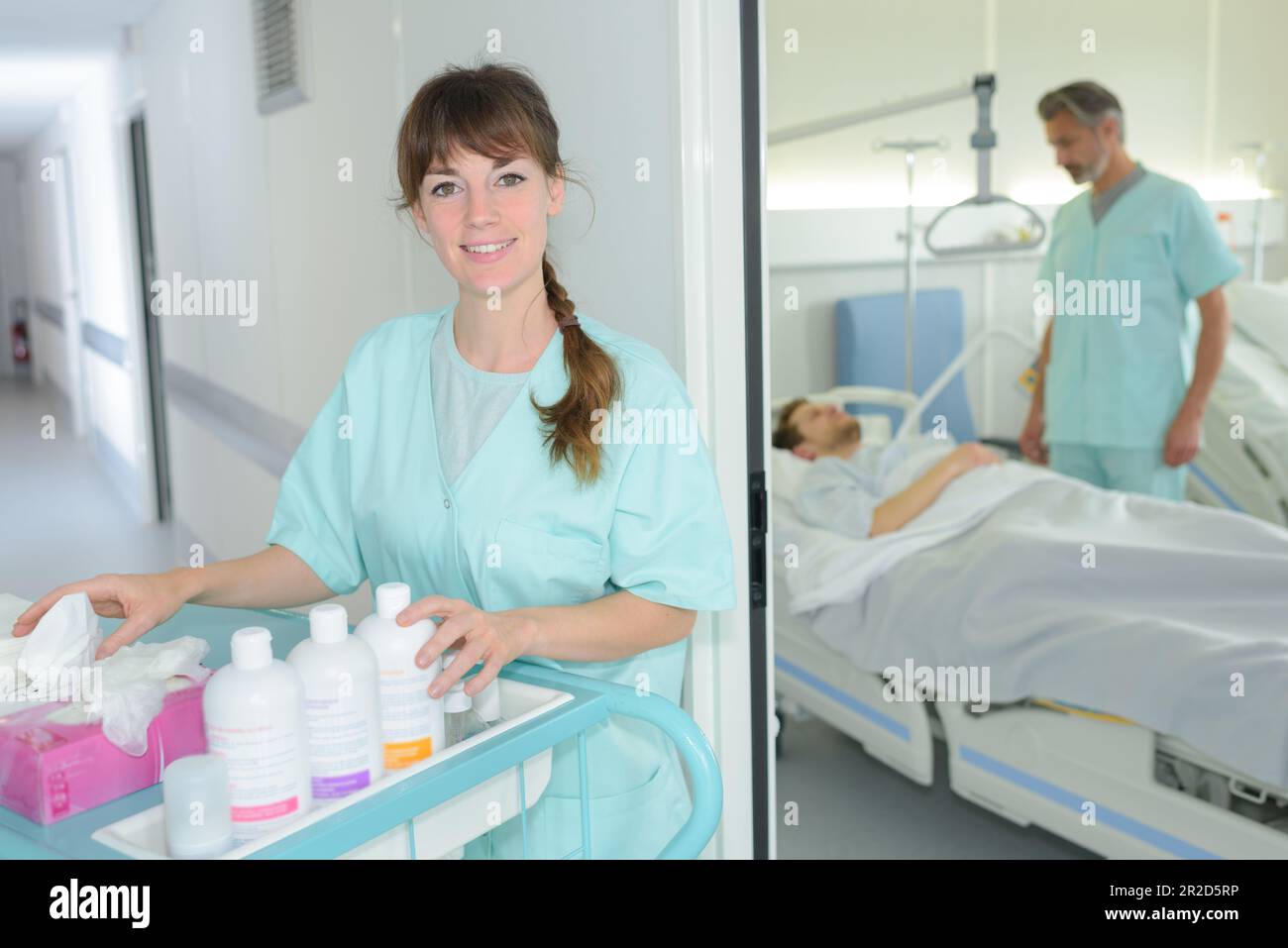 portrait of auxiliary nurse with trolley outside of patients room Stock Photo