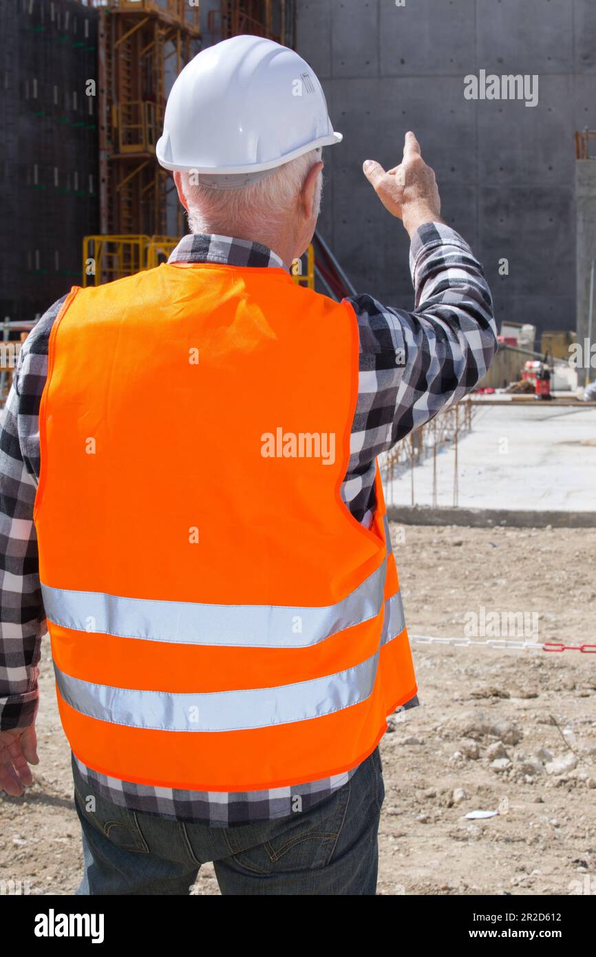 senior builder in hardhats pointing outdoors Stock Photo