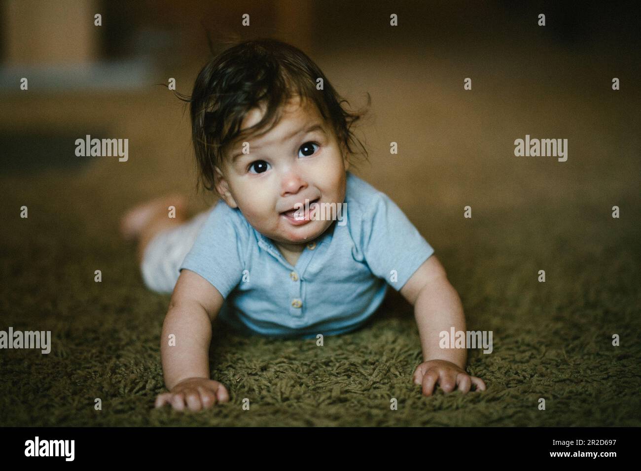 Happy baby crawl on stomach in his home and smiles Stock Photo