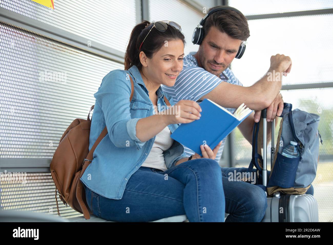 couple sitting at train station checking a book while waiting Stock Photo