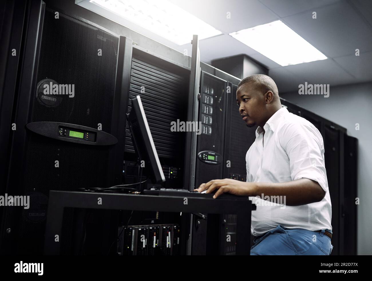 IT support, black man or coding on laptop in server room for big data, network glitch or digital website. Code, fixing or technician typing on Stock Photo