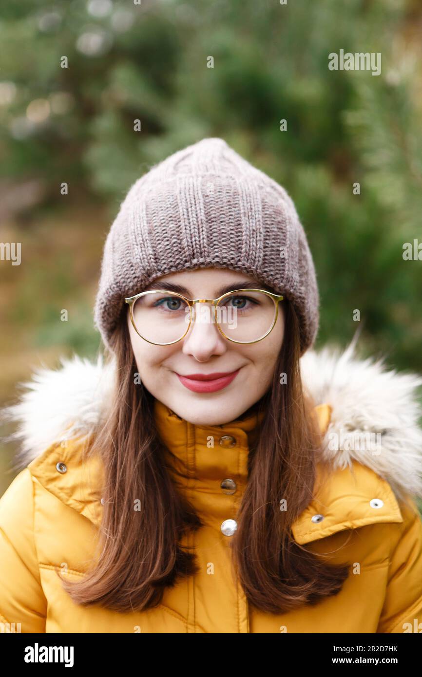 The portrait of the young female woman in a yellow winter jacket who is