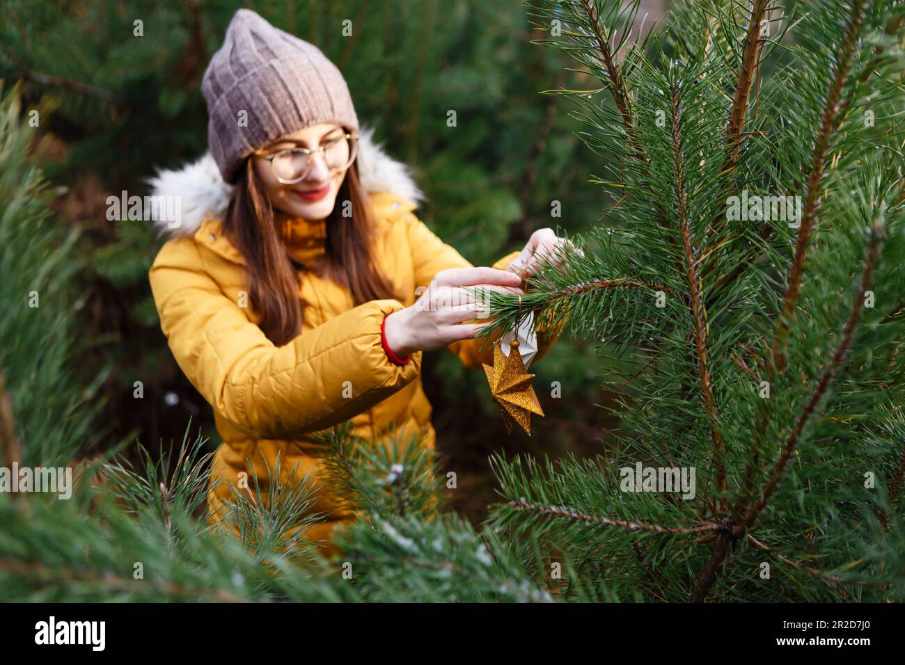 young woman hangs decorations on a christmas tree Stock Photo
