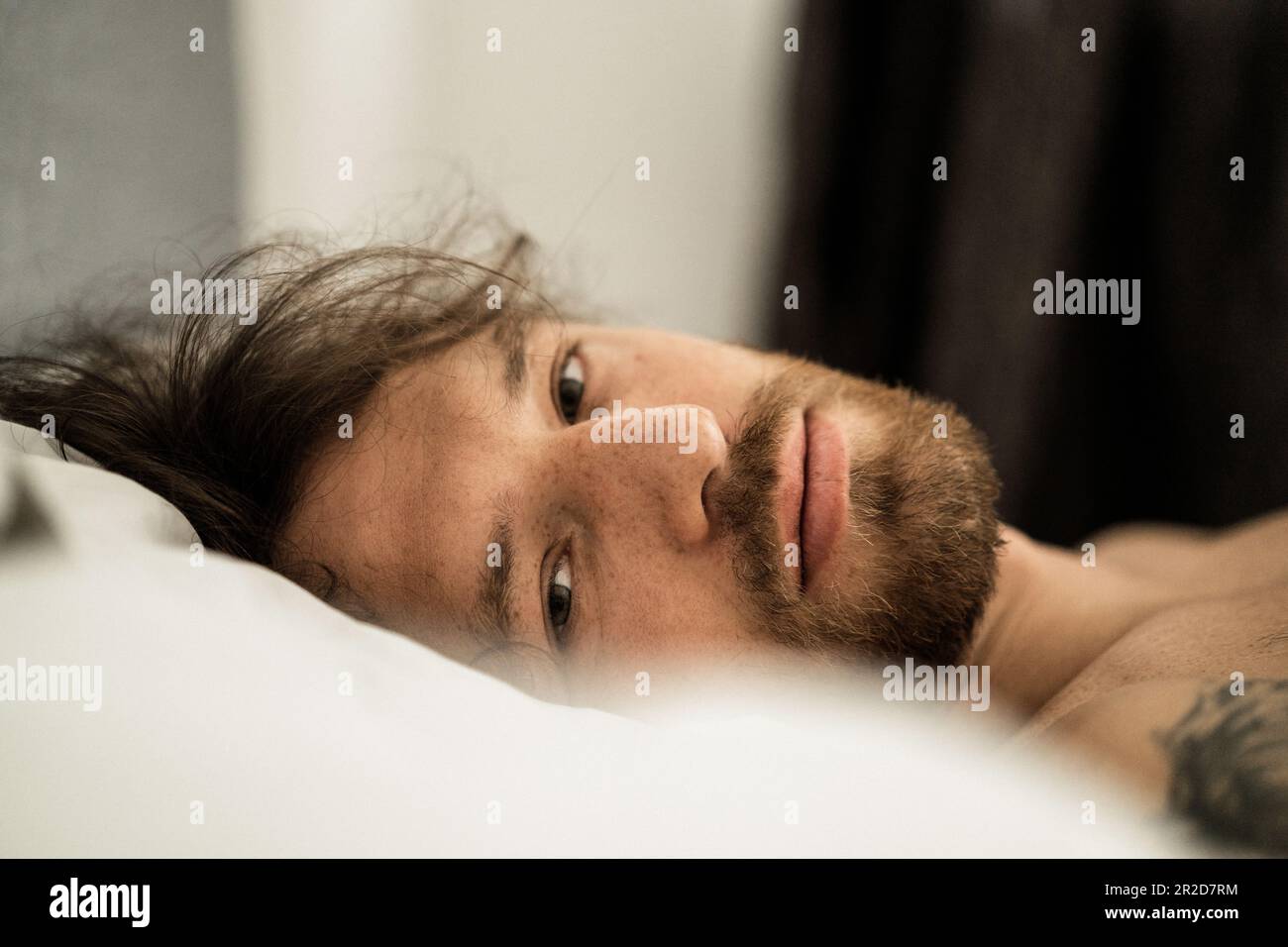 Handsome man in bed after sleep wakes up and starts a new day. Stock Photo