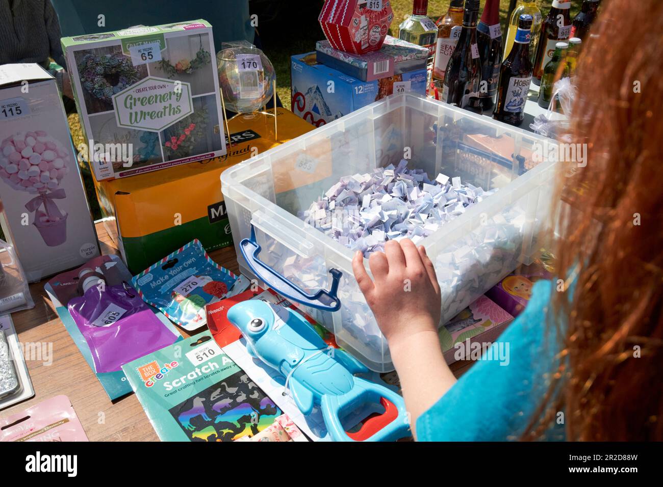 young girl pick tickets from bucket tombola stand at a local community summer fair simonswood england uk Stock Photo