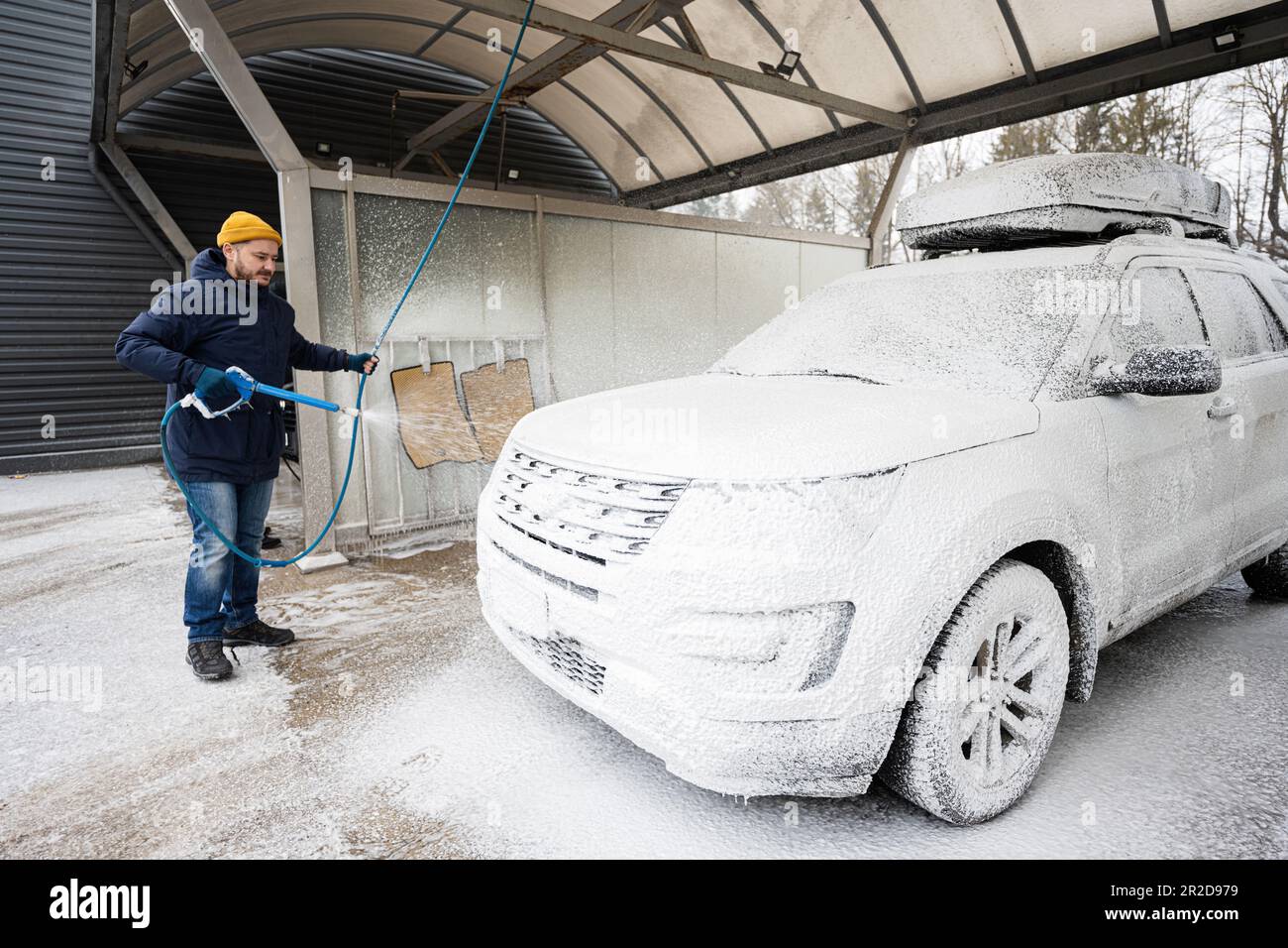 Man washing american SUV car with roof rack at a self service wash in